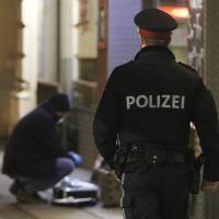 A police officer passes by a forensic expert after several people were wounded in a knife attack on the streets of Vienna Wednesday. | AP