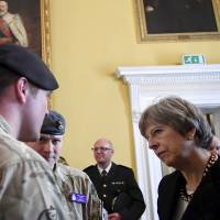 Prime Minister Theresa May speaks to members of military as she visits Salisbury in southwest England on Thursday. | AP