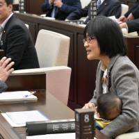 Kumamoto Municipal Assembly member Yuka Ogata holds her baby during a meeting of the legislature on Nov. 22. | KYODO