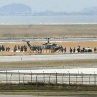 People surround a Ground Self-Defense Force helicopter after it made an emergency landing at Yonago Airport in Tottori Prefecture on Thursday. | KYODO