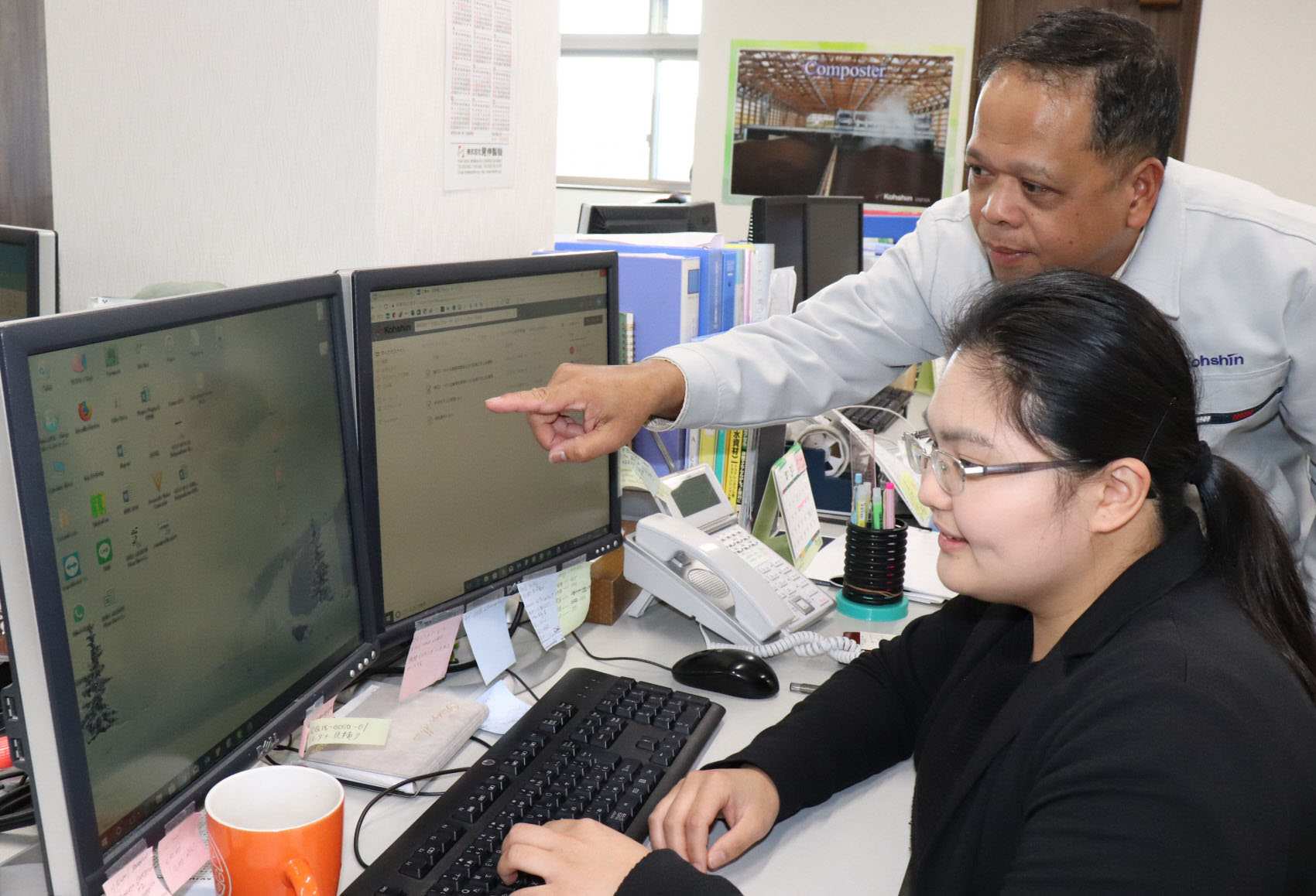 Kohshin Engineering Co. employee Mikee Rose Mejia from the Philippines receives instructions from fellow Filipino Arnolfo T. Tangi, who is in charge of sales in Southeast Asia, at the company headquarters in Ama, Aichi Prefecture. | CHUNICHI SHIMBUN