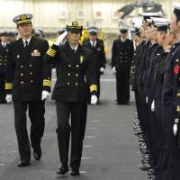 Ryoko Azuma (second from left), newly appointed commander of the 1st Escort Division of the Maritime Self-Defense Force and the first female commander of an MSDF destroyer squadron, gives a salute on the helicopter carrier Izumo at a port in Yokohama on Tuesday. | REUTERS