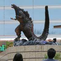 People look up at a new Godzilla statue, unveiled on Thursday at a shopping mall in central Tokyo. | KYODO