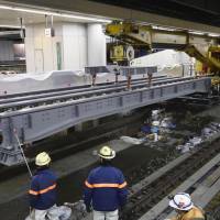 Construction workers put girders in place for the maglev track at Shinagawa Station in Tokyo in November. | KYODO