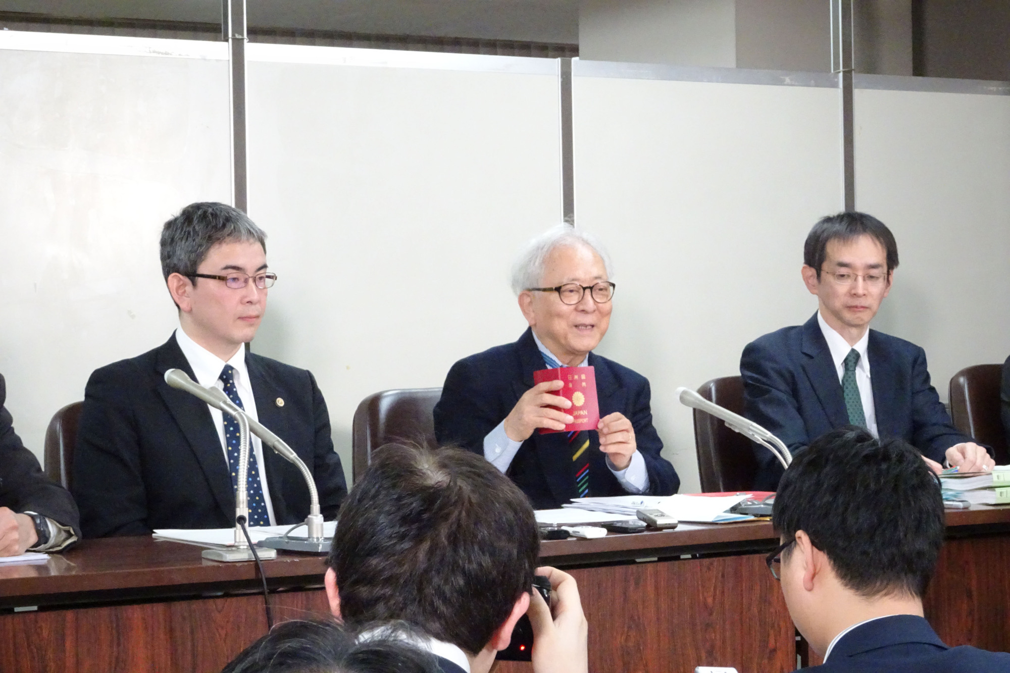 Hitoshi Nogawa, a plaintiff in a lawsuit targeting Japan's ban on dual citizenship, holds up his invalidated passport at a news conference in Tokyo on Monday, telling reporters that being forced to give up his nationality was a 'painful experience.' | SAKURA MURAKAMI