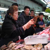 A clerk holds up an Ise-ebi (Japanese spiny lobster) at a market in Naha, Okinawa Prefecture. | THE OKINAWA TIMES