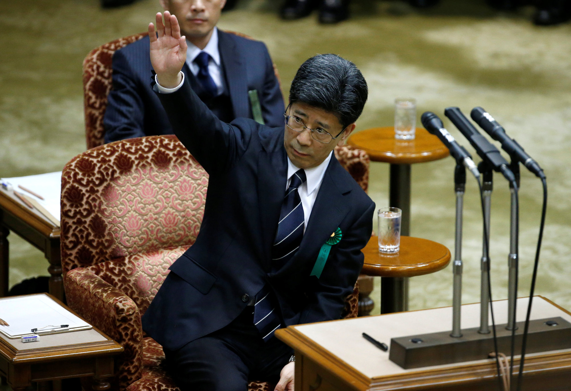 Former National Tax Agency chief Nobuhisa Sagawa, a key figure in a cronyism scandal that has sparked a political crisis for Prime Minister Shinzo Abe, raises his hand as he testifies at the Upper House of the Diet in Tokyo on Tuesday. | REUTERS