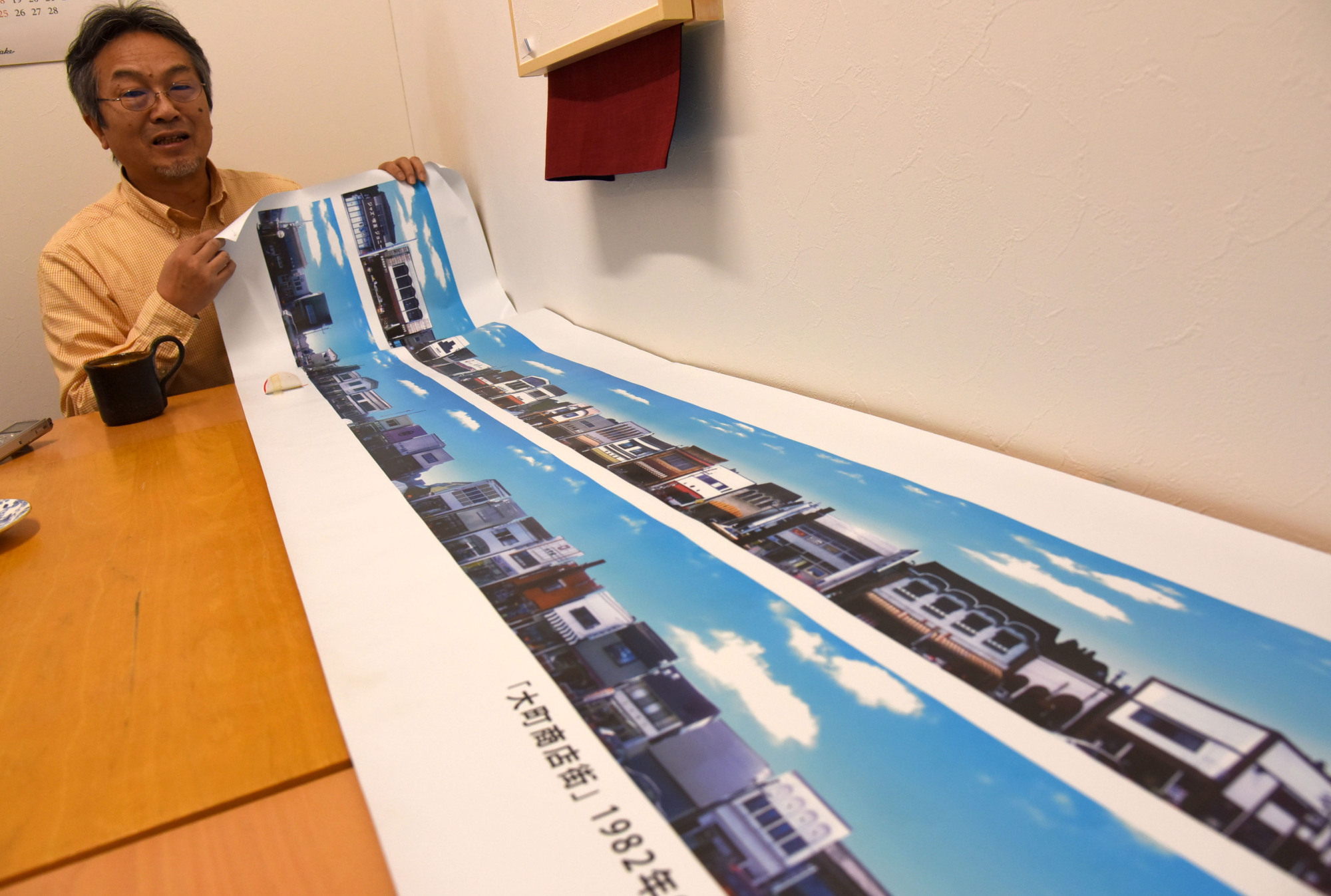 Seitoku Iwai, a 12th-generation shop owner in Rikuzentakata, Iwate Prefecture, shows an image of a shopping mall wiped out by the March 2011 tsunami, on Feb. 22. | SATOKO KAWASAKI