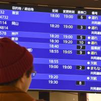 A man checks flight information on a screen at New Chitose Airport in Hokkaido on Thursday. | KYODO