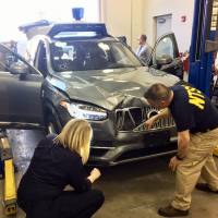 In this photo provided by the U.S. National Transportation Safety Board, investigators examine a driverless Uber SUV that fatally struck a woman in Tempe, Arizona, last Sunday night. | AP