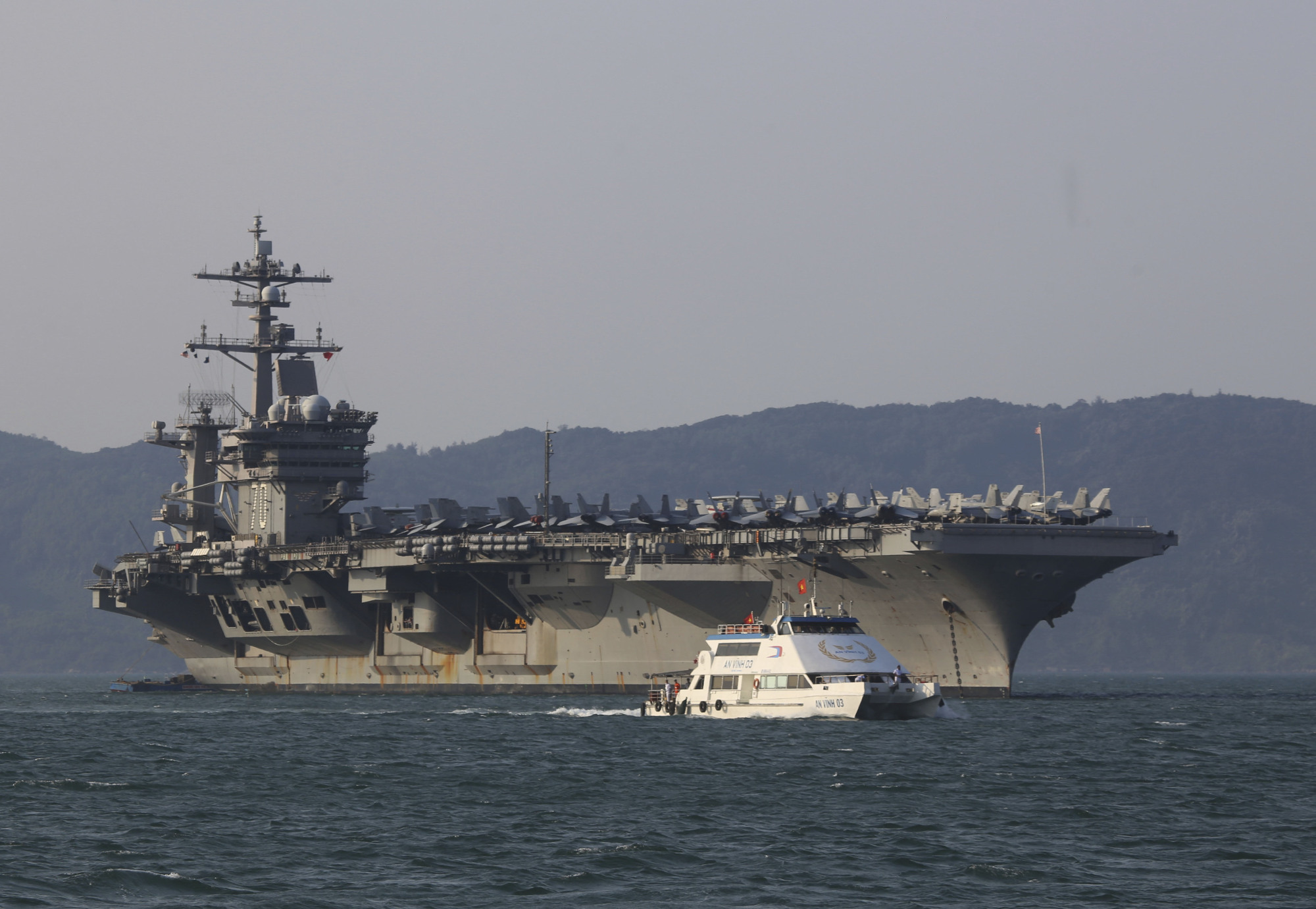 A Vietnamese passenger boat sails past the U.S. aircraft carrier USS Carl Vinson as it docks in Da Nang Bay, Vietnam, on March 5. The Carl Vinson recently completed the first visit to a Vietnamese port since the end of the Vietnam War. | AP