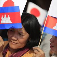 Cambodians hold the flags of Japan and their country as they listen to Prime Minister Hun Sen\'s speech Tuesday during the inauguration ceremony of a road funded by Japan at Kdey Takoy village, located on the outskirts of Phnom Penh. | AP