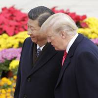 U.S. President Donald Trump and Chinese President Xi Jinping chat during a welcome ceremony outside the Great Hall of the People in Beijing on Nov. 9. | BLOOMBERG