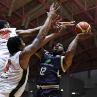Ryukyu\'s Hassan Martin takes a shot while being double-teamed by Osaka\'s Xavier Gibson (left) and Keith Benson in the fourth quarter on Friday night in Okinawa City. The Golden Kings beat the Evessa 78-66. | B. LEAGUE