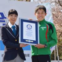 Marathon runner Yuki Kawauchi receives a certificate from Guinness World Records on Sunday recognizing his achievement in completing the highest number of marathons in under 2 hours, 20 minutes. | KYODO