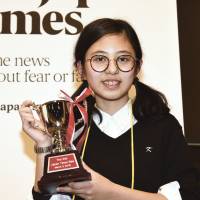 Hanna Yoshida from K. International School Tokyo poses with her trophy on Saturday after winning the ninth Japan Times Bee at the newspaper\'s headquarters in Tokyo. Yoshida correctly spelled insubordinate to secure the right to represent Japan at the Scripps National Spelling Bee in Washington in May. | SATOKO KAWASAKI