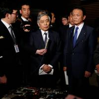 Bank of Japan Gov. Haruhiko Kuroda (center) speaks to the media with Deputy Prime Minister and Finance Minister Taro Aso (second from right) and economic and fiscal policy minister Toshimitsu Motegi (right) after meeting with Prime Minister Shinzo Abe at the Prime Minister\'s Office on Monday. | AP