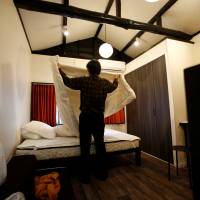 Yasuhiro Inaoka, who manages apartments for owners who provide short-term lodging services, arranges a bed after guests checked out at a Tokyo apartment that is listed on Airbnb. | REUTERS