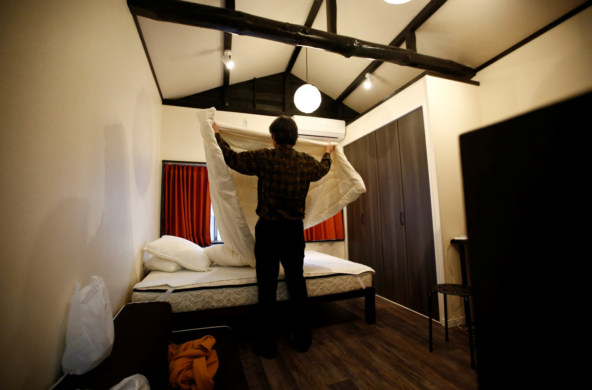 Yasuhiro Inaoka, who manages apartments for owners who provide short-term lodging services, arranges a bed after guests checked out at a Tokyo apartment that is listed on Airbnb. | REUTERS