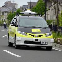 A self-driving delivery vehicle moves down a closed-off street during an experiment by Yamato Transport Co. and DeNA Co. in Fujisawa, Kanagawa Prefecture, on Tuesday. | KAZUAKI NAGATA