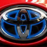 The Toyota logo is seen on the trunk of a 2018 Toyota Prius on display at the Pittsburgh Auto Show in February. Toyota says it will start equipping models with technology to talk to other vehicles starting in 2021, as it tries to push safety communications forward. | AP