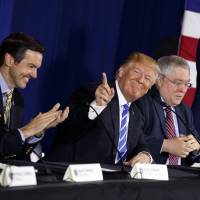 President Donald Trump smiles as people applaud him during a roundtable discussion on tax policy Thursday in White Sulphur Springs, West Virginia with (from left) Rep. Evan Jenkins, R-W.Va., West Virginia Attorney General Patrick Morrisey and CEO of Davis Trust Company Hugh Hitchcock. | AP