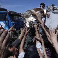 Syrian authorities distribute bread, vegetables and pasta to residents of Douma &#8212; the site of a suspected chemical weapons attack &#8212; near Damascus, Syria, on Monday. | AP