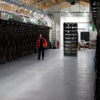 A worker walks along a row of computer rigs that run around the clock \"mining\" bitcoin inside the Genesis Mining cryptocurrency mine in Keflavik, Iceland, in January. A prisoner in Iceland suspected of masterminding the theft of about 600 computers used to mine bitcoin has managed to escape custody and flee the remote North Atlantic nation on a passenger plane. Police said surveillance footage showed a suspect they identified as Sindri Thor Stefansson boarding a passenger plane to Sweden on Tuesday. | AP