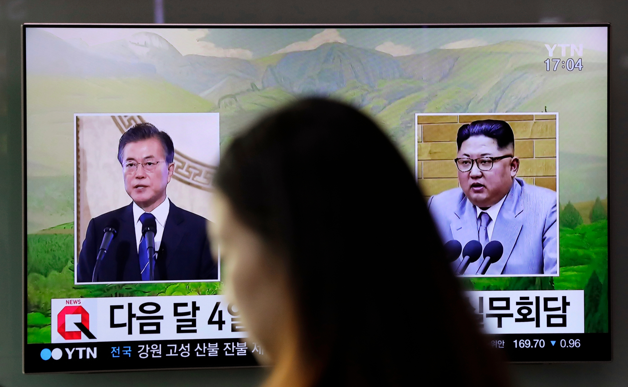 A news program shows file footage of South Korean President Moon Jae-in and North Korean leader Kim Jong Un on a TV screen at the main railway station in Seoul on March 29. | AP