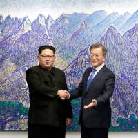 North Korean leader Kim Jong Un and South Korean President Moon Jae-in shake hands in the Peace House building on the southern side of the truce village of Panmunjom on Friday. | AFP-JIJI