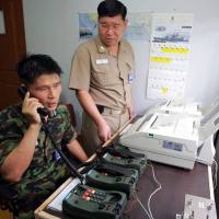 South Korean Lt. Choi Don-Rim communicates with a North Korean officer during a phone call at a military office near the Demilitarized Zone in Paju on Aug. 10, 2005, as the two countries test a hotline aimed at helping avoid naval confrontations in the Yellow Sea. | AFP-JIJI