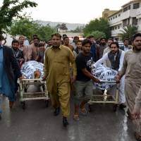 Pakistani Christian mourners push stretchers carrying the bodies of relatives who were killed in a drive-by shooting outside a church, at a hospital in Quetta on Sunday. | AFP-JIJI