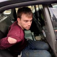 Travis Reinking, the suspect in a Waffle House shooting in Nashville, is seen under arrest by the Metro Nashville Police Department in a wooded area in Antioch, Tennessee, on Monday. | METRO NASHVILLE POLICE DEPARTMENT / VIA REUTERS