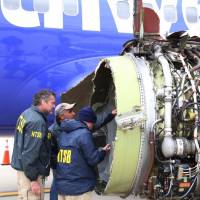 National Transportation Safety Board investigators examine damage to the engine of a Southwest Airlines plane that made an emergency landing at Philadelphia International Airport on Tuesday. | AP