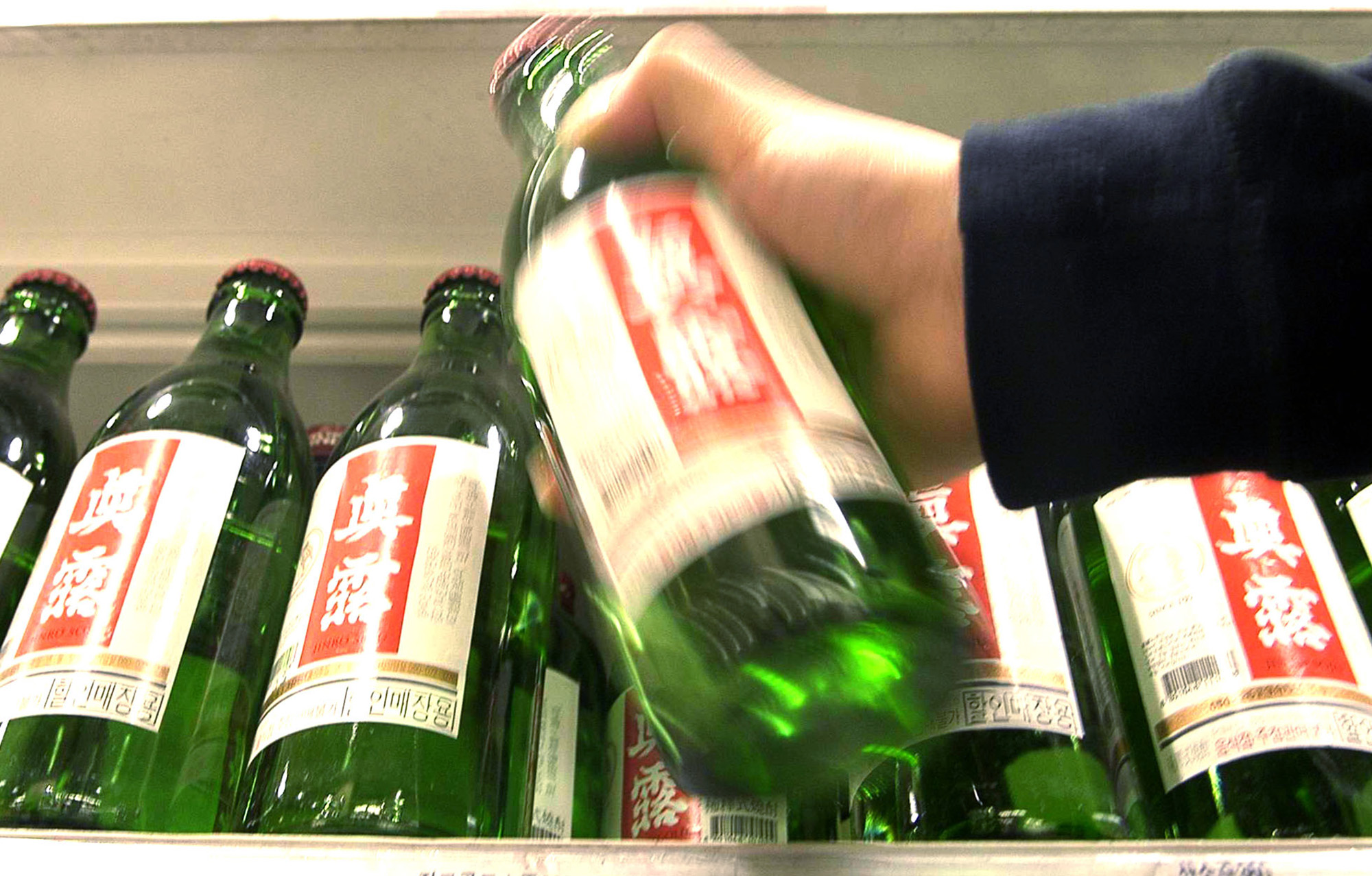 A sales clerk arranges soju liquor bottles at a store in Seoul. South Korea's Ministry of Food and Drug Safety said Tuesday that mixing wasps and the alcoholic beverage could pose health risks for habitual drinkers after the concoction gained popularity on the internet. | BLOOMBERG