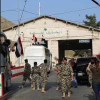 Members of the Lebanese General Security Directorate clear buses carrying Syrian refugees evacuated from the southern Lebanese village of Shebaa as they pass through the Masnaa crossing on the Lebanon-Syria border leading to Damascus on Wednesday. | AFP-JIJI