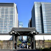 Tourists walk through the Otemon gate of the Imperial Palace against a backdrop of skyscrapers on April 19. | YOSHIAKI MIURA