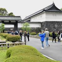 Tourists take photos in front of the Otemon gate at the Imperial Palace in April. | YOSHIAKI MIURA