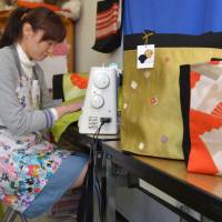 A woman at an establishment that employs people with disabilities in Nagoya uses a sewing machine to create a bag from a distinctively patterned Nagoya obi. | CHUNICHI SHIMBUN