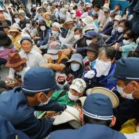 Protesters hold a sit-in at a gate in front of Camp Schwab, a U.S. Marine Corps facility, in Nago, Okinawa Prefecture, on Wednesday. | KYODO