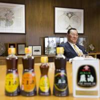 Jiro Ozawa, president and CEO of Kadoya Sesame Mills Inc., speaks as bottles of the company\'s sesame oil stand on a desk during an interview in Tokyo on Feb. 21. | BLOOMBERG