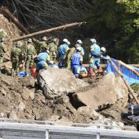 Police officers on Monday search for missing people at the site of last week\'s mudslide in Nakatsu, Oita Prefecture. | KYODO