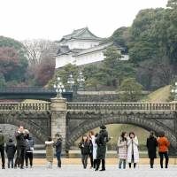 Tourists walk around the Imperial Palace in Tokyo in December 2017. English-speaking guides will be available for tours from the beginning of May. | KYODO