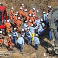 Rescuers search for survivors Thursday at the site where a massive landslide engulfed four houses the previous day in Nakatsu, Oita Prefecture. | KYODO