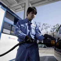 An employee inserts the nozzle of a hydrogen pump into a Toyota Motor Corp. Mirai fuel cell vehicle (FCV) during a demonstration at the Kawasaki Hydrogen Station in Kawasaki in March. | BLOOMBERG