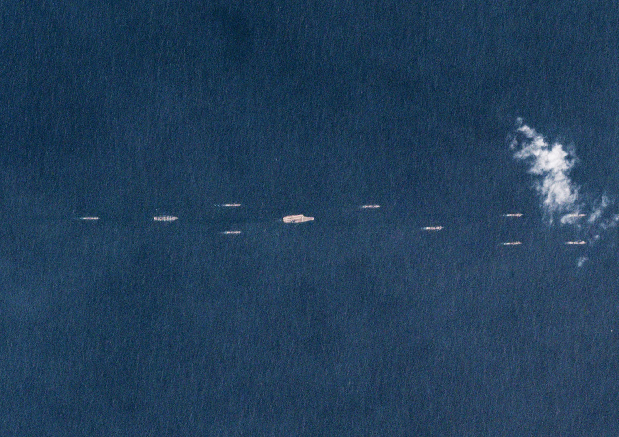 China's sole operational aircraft carrier, the Liaoning (center), is shown sailing with other ships at sea just south of Hainan Island on March 26 in a satellite photo released March 30. Beijing has been flexing its military muscles in recent days, conducting massive naval drills in the South China Sea. | AFP-JIJI