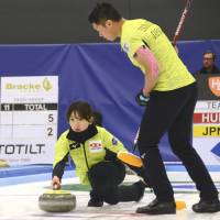 Satsuki Fujisawa launches a stone as teammate Tsuyoshi Yamaguchi watches on Saturday at the World Mixed Doubles Curling Championship in Oestersund, Sweden. | KYODO