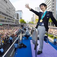 Two-time Olympic gold medalist Yuzuru Hanyu waves to the crowd during a victory parade on Sunday in Sendai. | AFP-JIJI