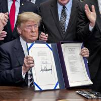 U.S. President Donald Trump holds up S. 2155, the Economic Growth, Regulatory Relief, And Consumer Protection Act, after being signed with administration officials and members of Congress in the Roosevelt Room of the White House in Washington on Thursday. The House Tuesday voted 258-to-159 to send Trump the most significant overhaul of banking oversight to become law since Dodd-Frank was enacted in 2010. | BLOOMBERG