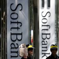 SoftBank Group Corp. store employees are seen working outside a branch in Tokyo in 2015. SoftBank logged a record annual operating profit for the business year that ended in March. | REUTERS